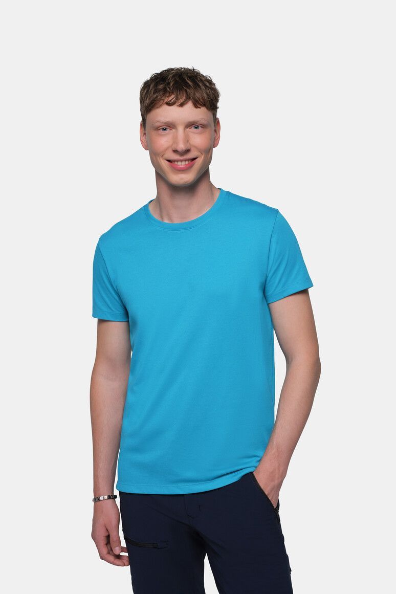Mann in blauem T-Shirt und marineblauer Hose, lächelnd, vor weißem Hintergrund stehend.