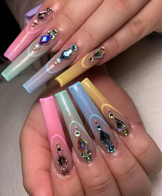Las uñas de una mujer son muy largas y coloridas con diamantes de imitación.