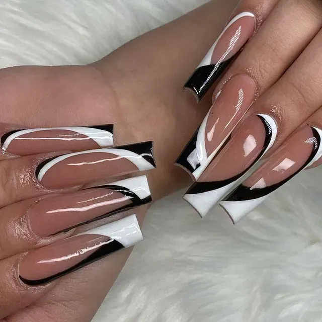 La mano de una mujer con largas uñas blancas y negras