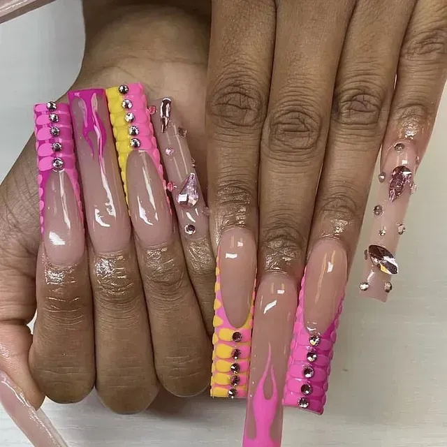 Un primer plano de las uñas de una mujer con diseños rosas y amarillos.