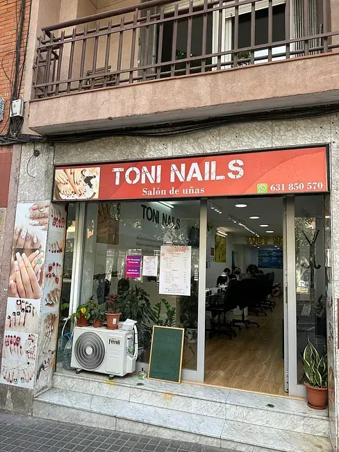 El frente de un salón de uñas Toni con balcón.