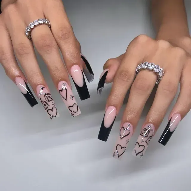Un primer plano de las uñas de una mujer con corazones en ellas.