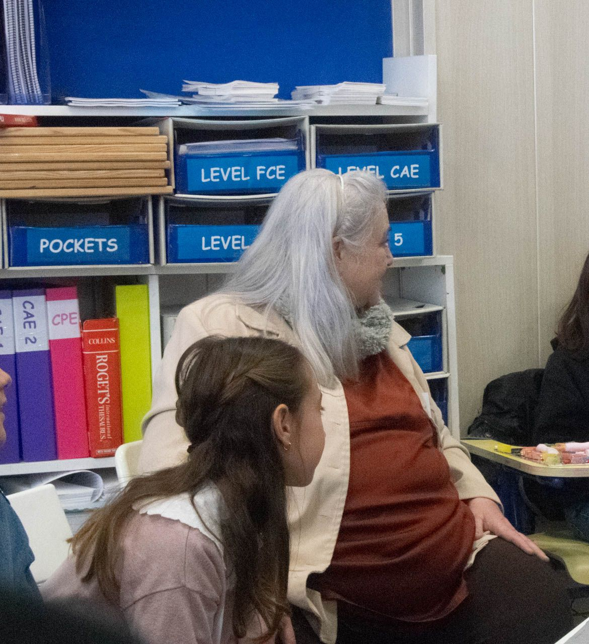Profesor señala ecuaciones en una pizarra frente a una clase de estudiantes.