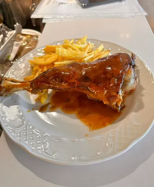 Un plato blanco cubierto con un trozo de carne y patatas fritas.