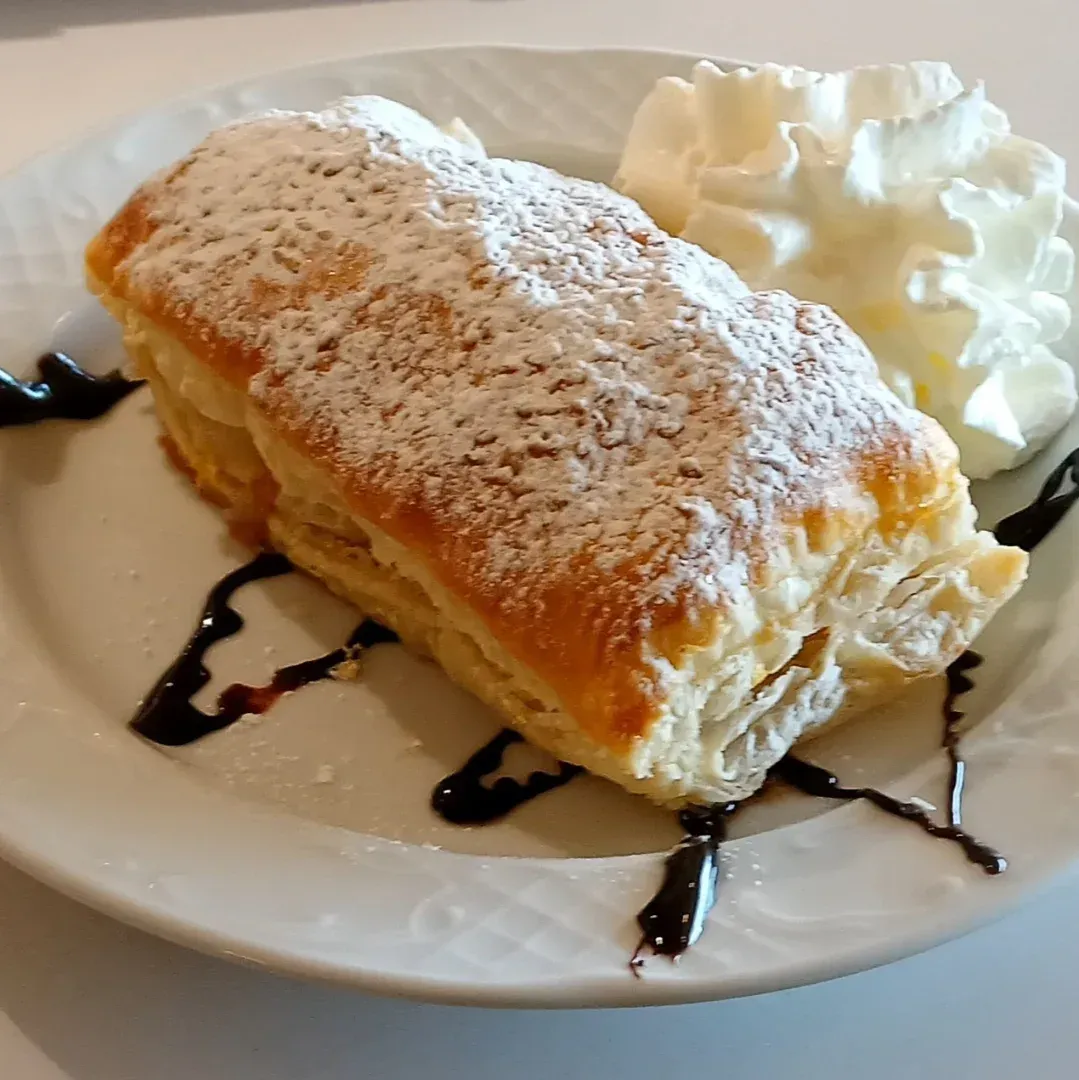 Un plato blanco cubierto con una masa y crema batida