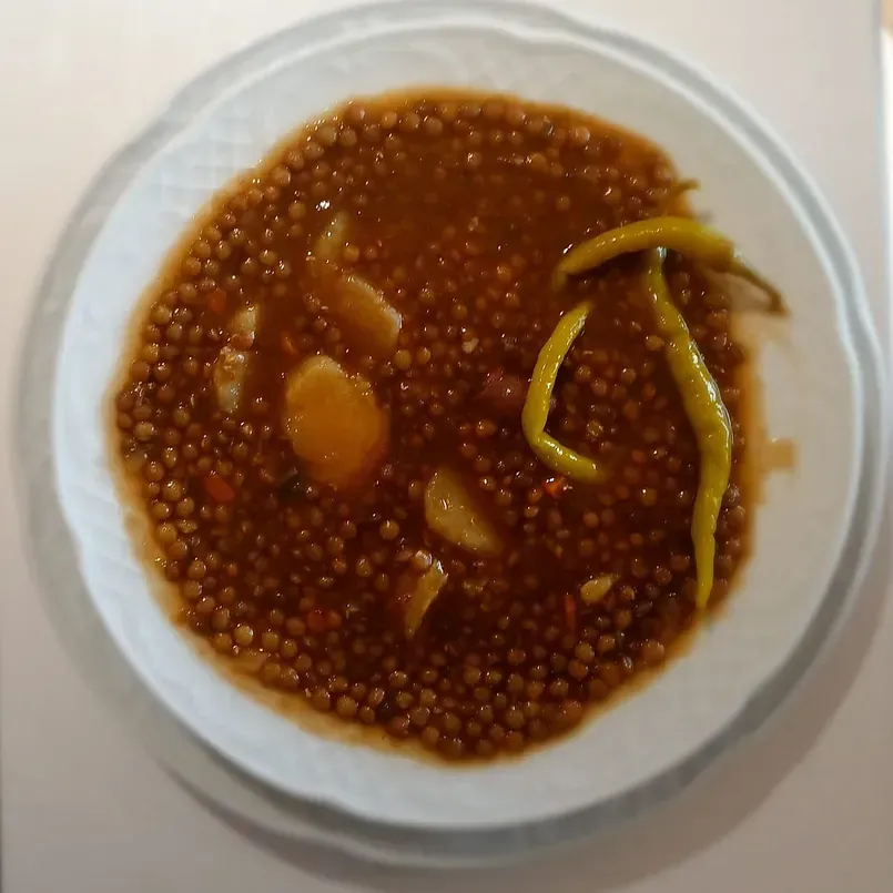 Un plato blanco cubierto con un guiso de frijoles y pimientos.