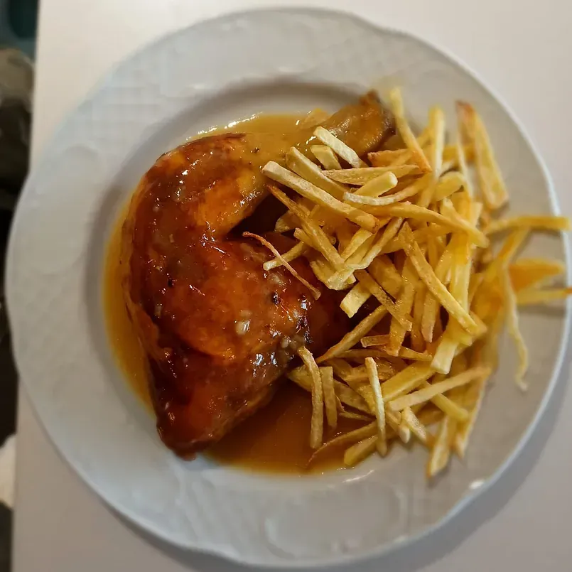 Un plato blanco cubierto con pollo y papas fritas