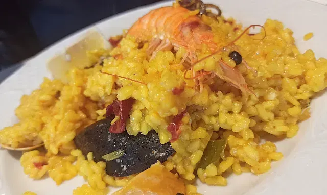 Un primer plano de un plato blanco cubierto con arroz y camarones.