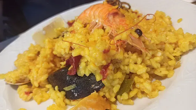 Un primer plano de un plato blanco cubierto con arroz y camarones.