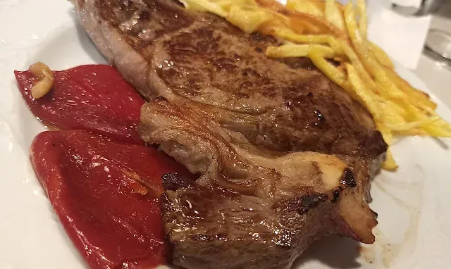 Un primer plano de un plato de comida con carne y verduras sobre una mesa.
