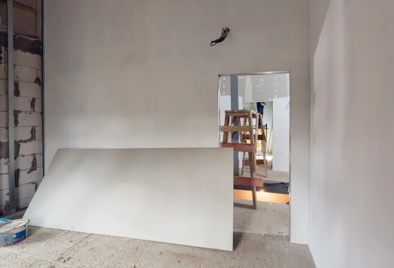 Habitación interior en construcción, con paneles de yeso apoyados contra una pared