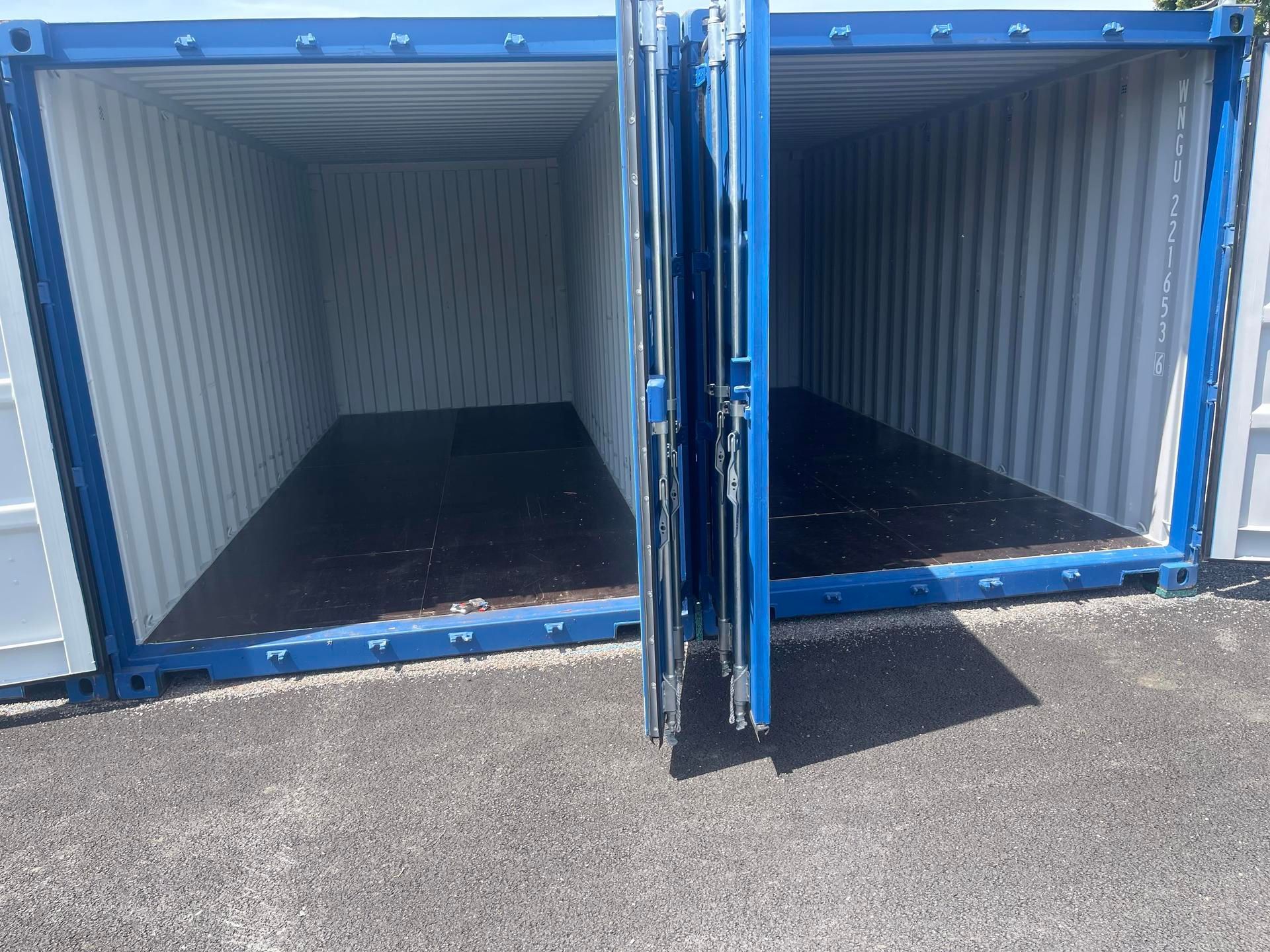 Deux conteneurs bleus, portes ouvertes dont l'intérieur est vide.