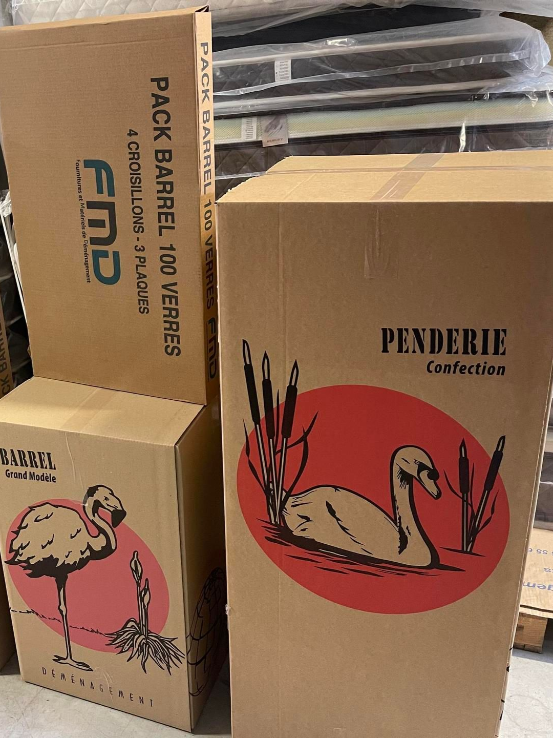 Des boîtes en carton empilées, ornées d'illustrations de flamants roses et de cygnes.