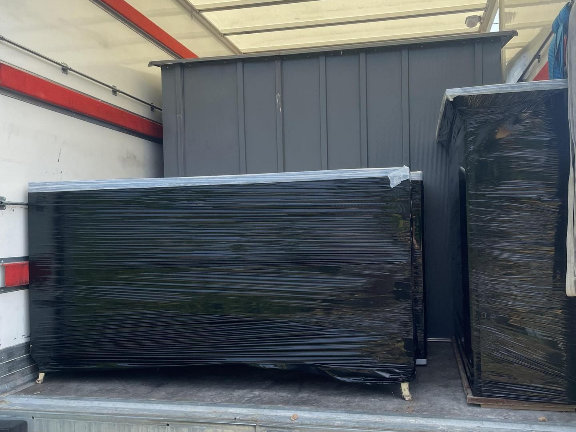 Des cartons emballés dans du plastique noir se trouvent à l'intérieur d'un camion.