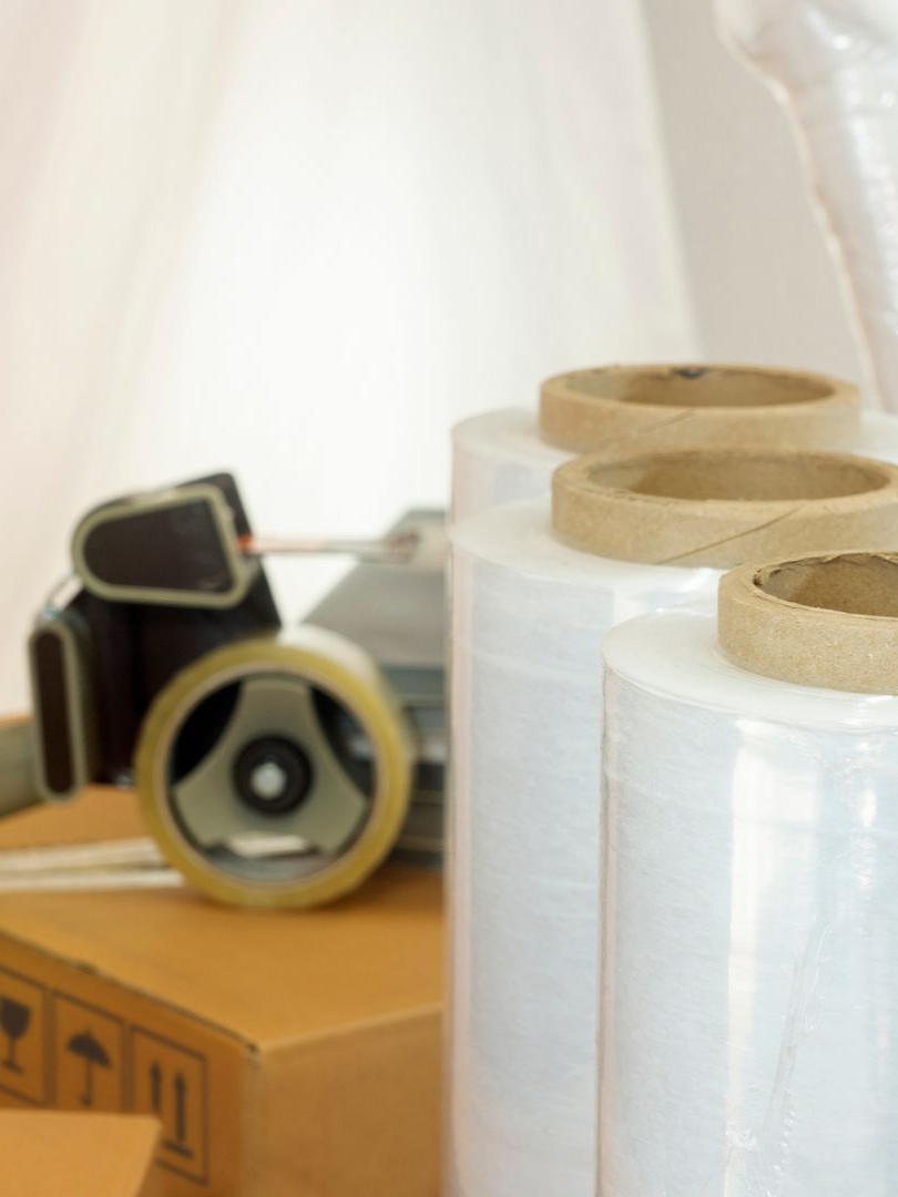 Cartons, dérouleur de ruban adhésif d'emballage et rouleaux de films étirables.