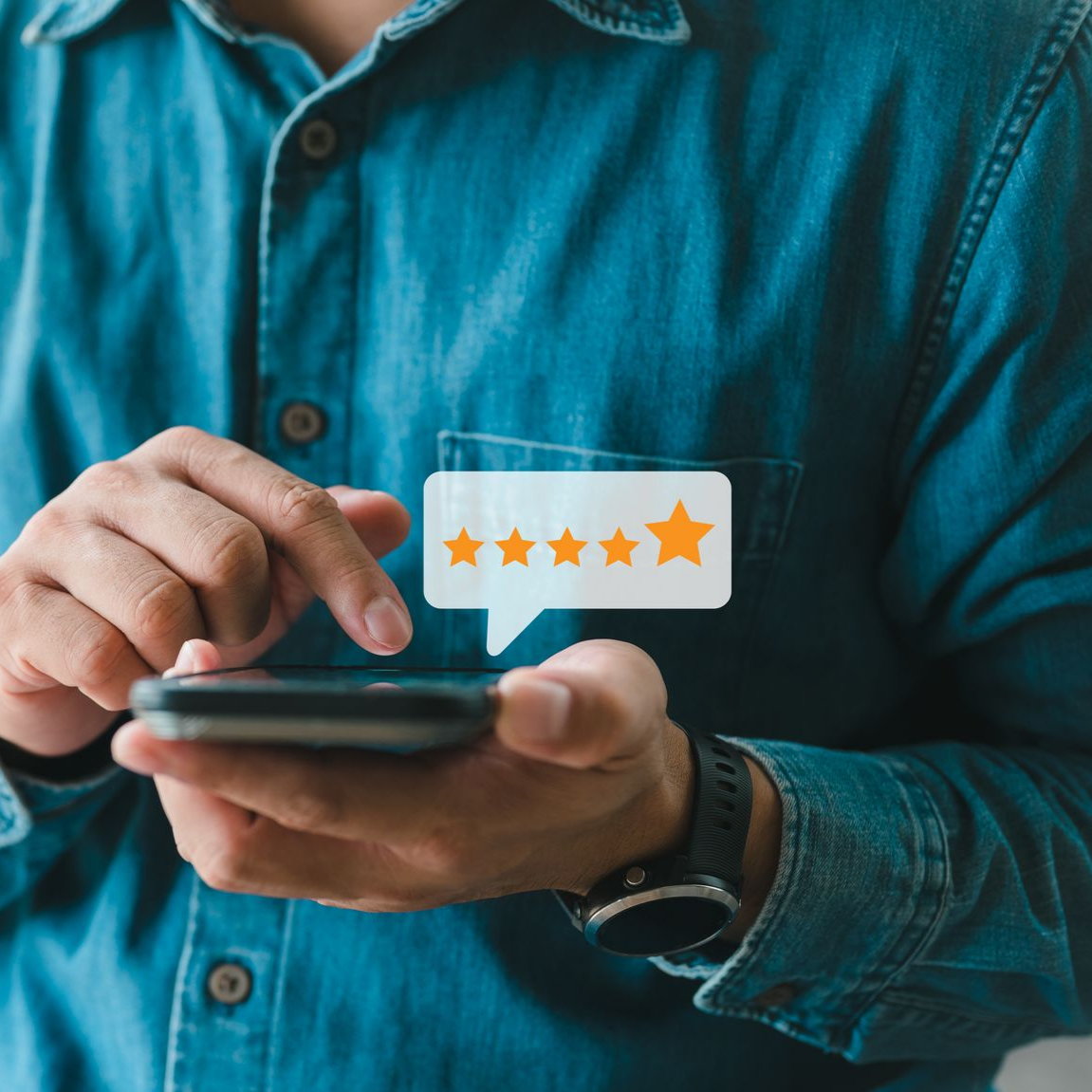Une personne en chemise bleue tenant un téléphone donne un avis 5 étoiles.