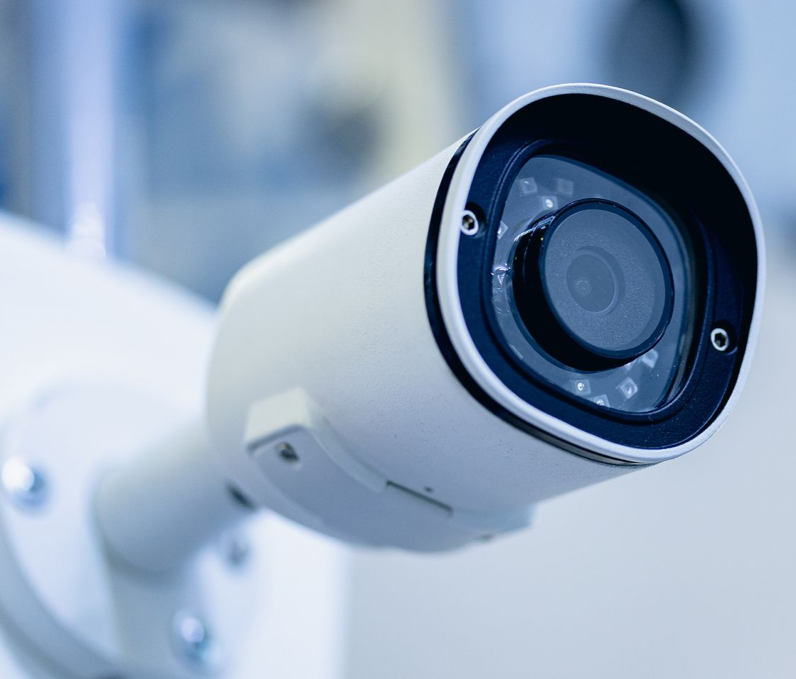 Caméra de sécurité blanche, orientée vers l'extérieur.
