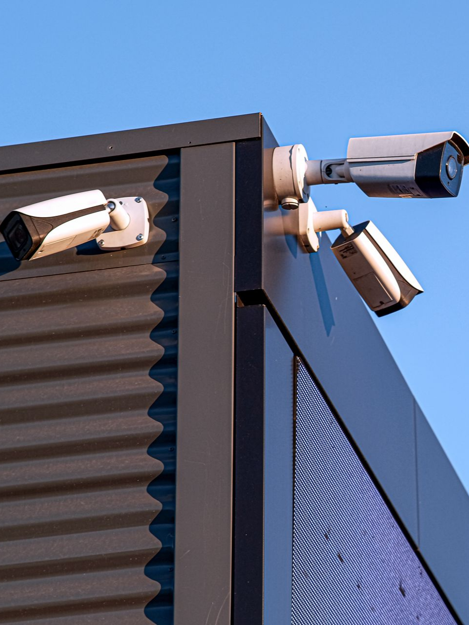 Trois caméras de sécurité fixées sur un coin de bâtiment.