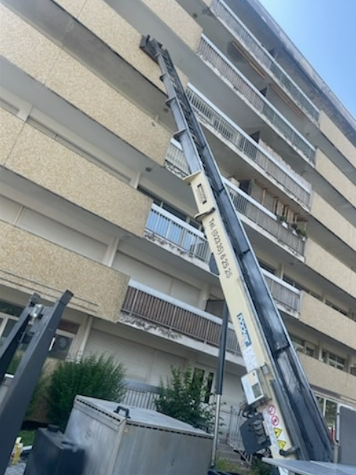 Une nacelle surplombe un immeuble d'habitation.