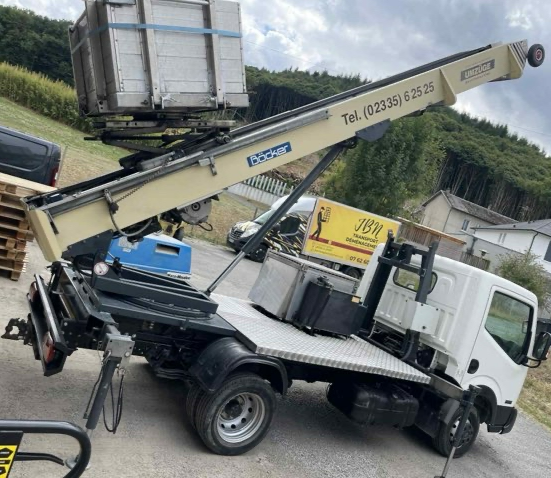 Nacelle montée sur camion soulevant un grand conteneur.