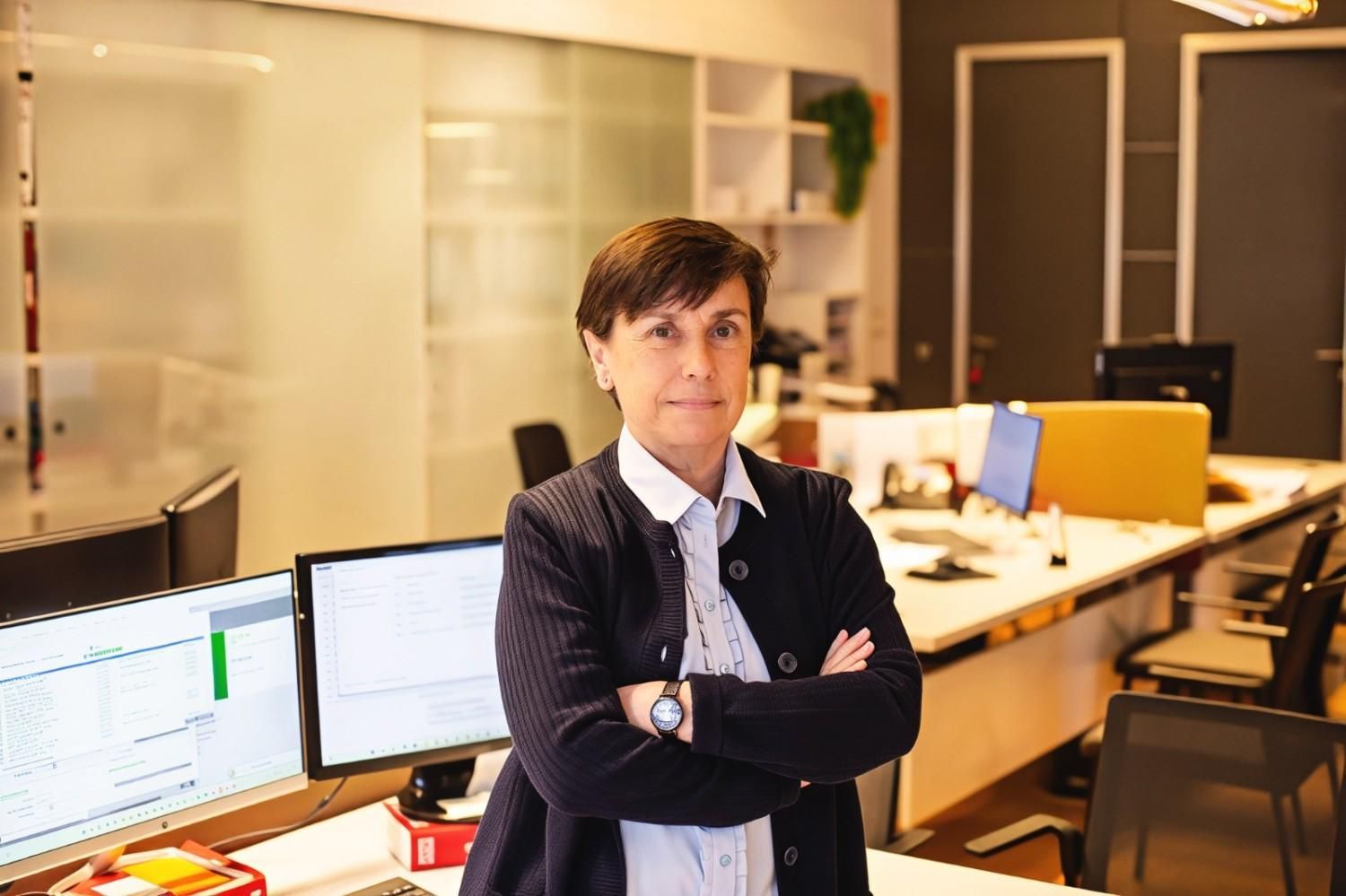 Mujer sosteniendo un receptor de teléfono, mirando hacia la cámara, entorno interior.