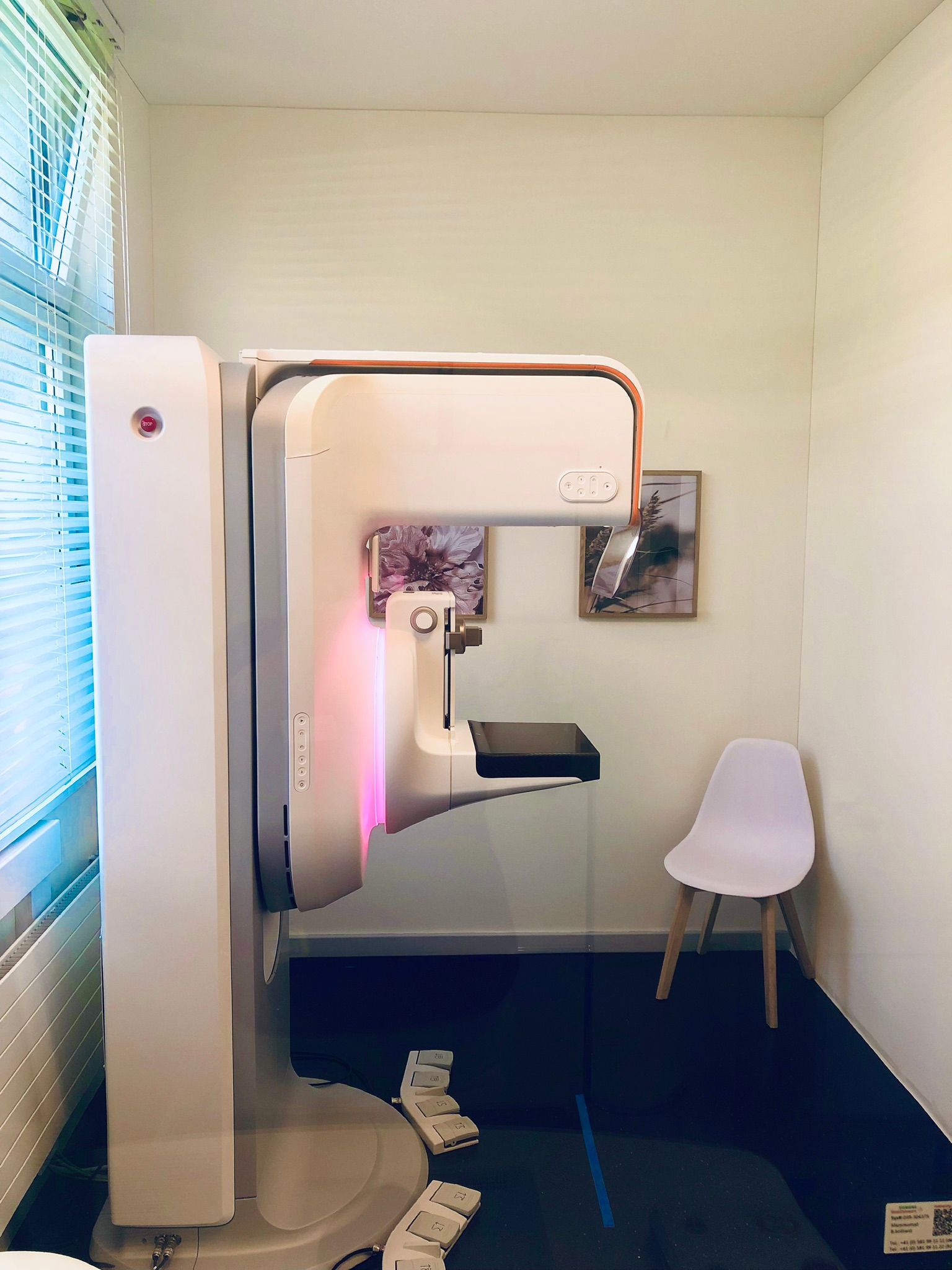 Ein Raum mit einem Stuhl und einer Mammographie Screening Maschine darin.