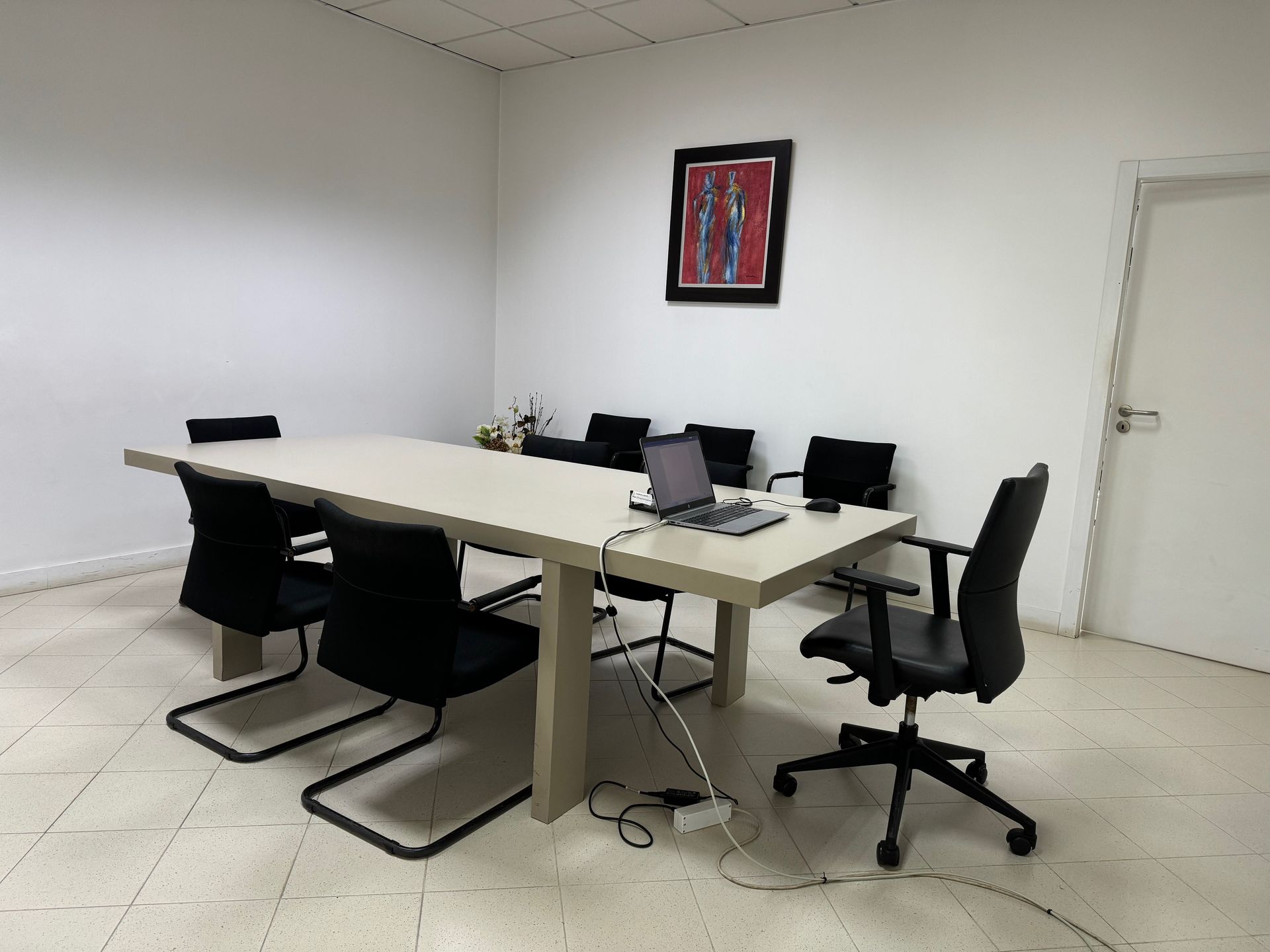Uma sala de conferências com uma mesa longa, cadeiras e um laptop sobre a mesa