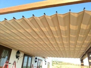 Toldo de patio a rayas beige extendido sobre la terraza de una casa bajo un cielo azul