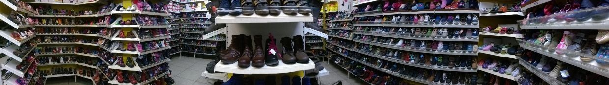 Ein Gang in einem Schuhgeschäft, an beiden Seiten Reihen von Turnschuhen und in der Mitte ein Präsentationstisch.