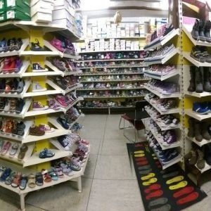 Ein Schuhladengang mit Reihen bunter Schuhe in Regalen und einer schwarzen Matte auf dem Boden.
