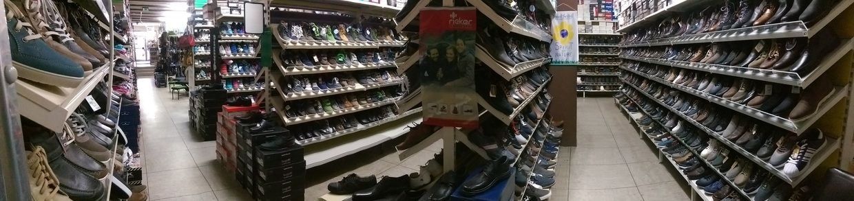 Ein Gang in einem Schuhgeschäft mit Regalreihen, die auf beiden Seiten voll mit Schuhen sind.