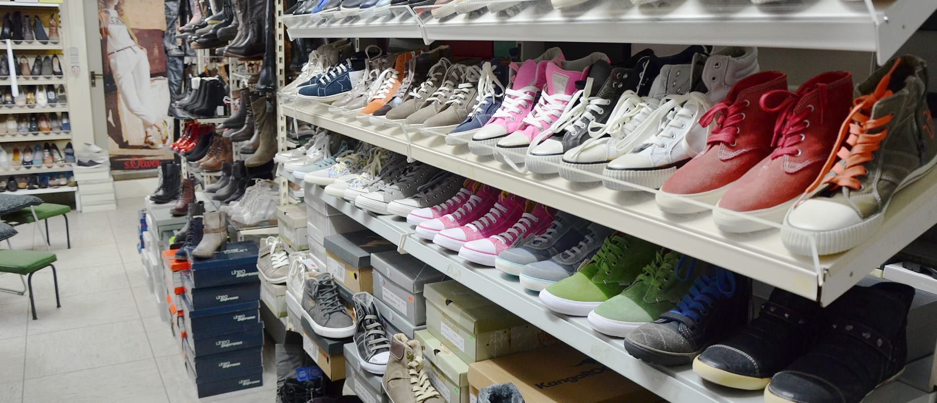 Gang in einem Schuhgeschäft mit Reihen bunter Turnschuhe und Kartons in den Regalen