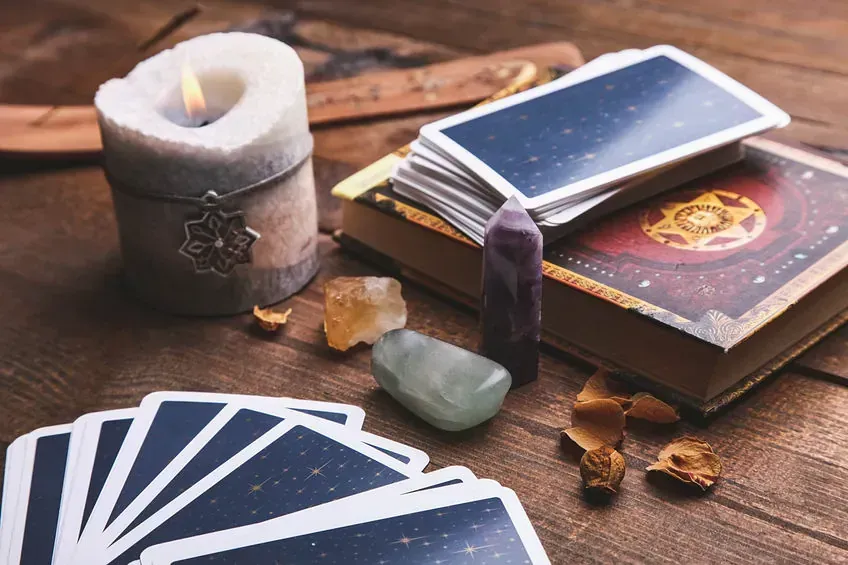 Una configuración de lectura de cartas del tarot con velas, cristales, un libro y una baraja de cartas.