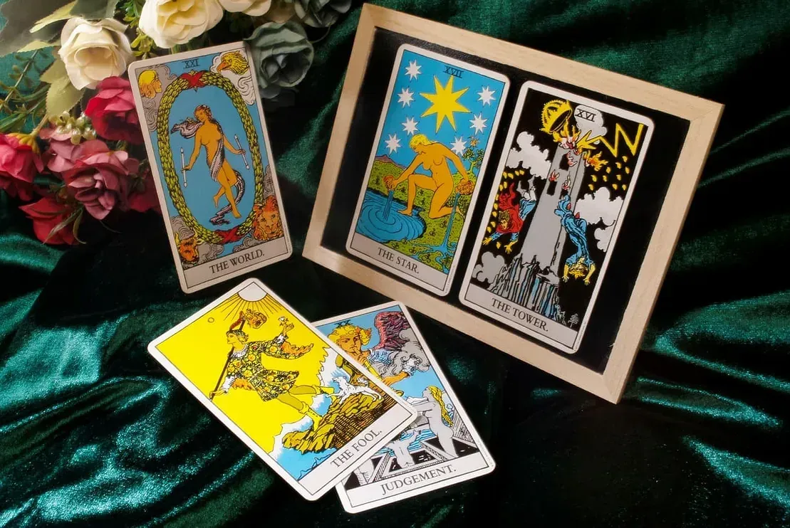 Cartas del Tarot sobre terciopelo verde. Se muestran el Mundo, la Estrella, la Torre, el Carro y otras.