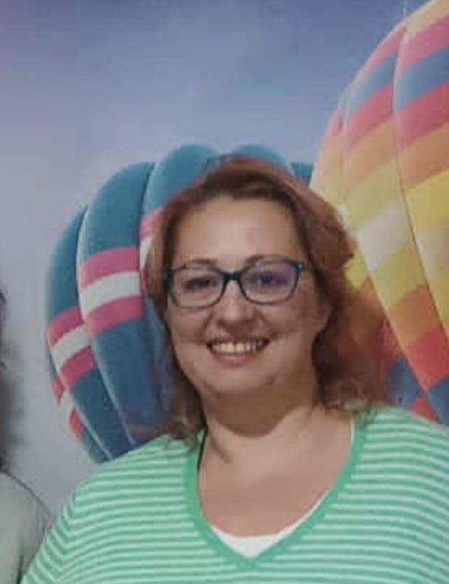 Una mujer con gafas sonríe delante de una imagen de globos aerostáticos.