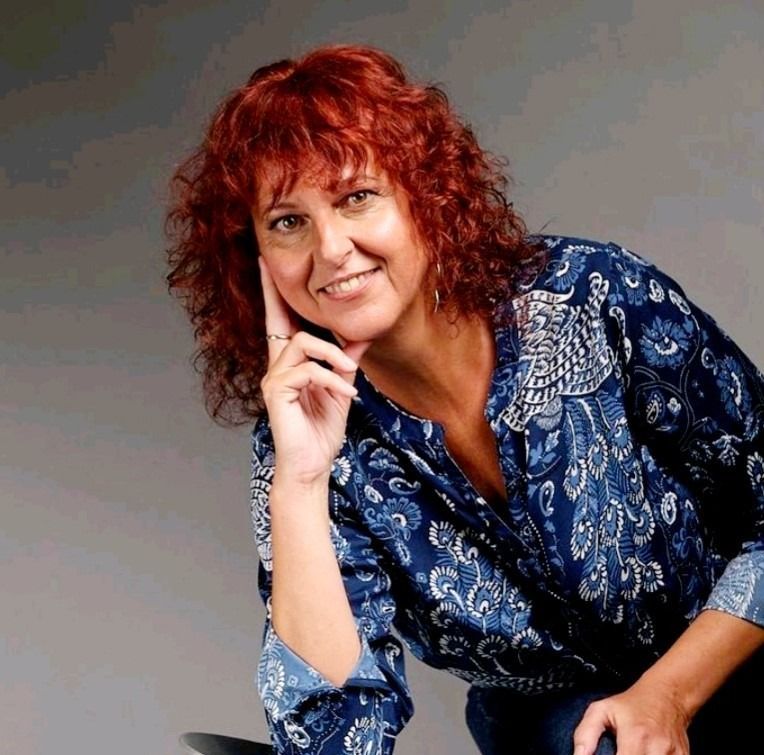 Una mujer pelirroja lleva una camisa azul.