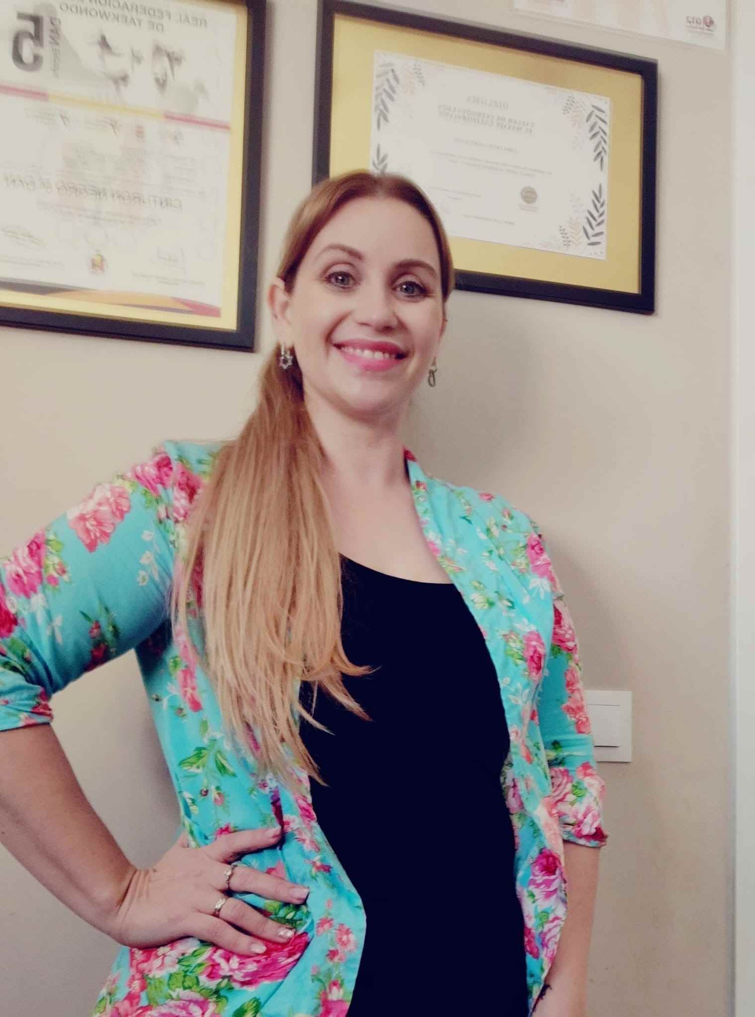 Una mujer que lleva una chaqueta floral y un vestido negro sonríe a la cámara.