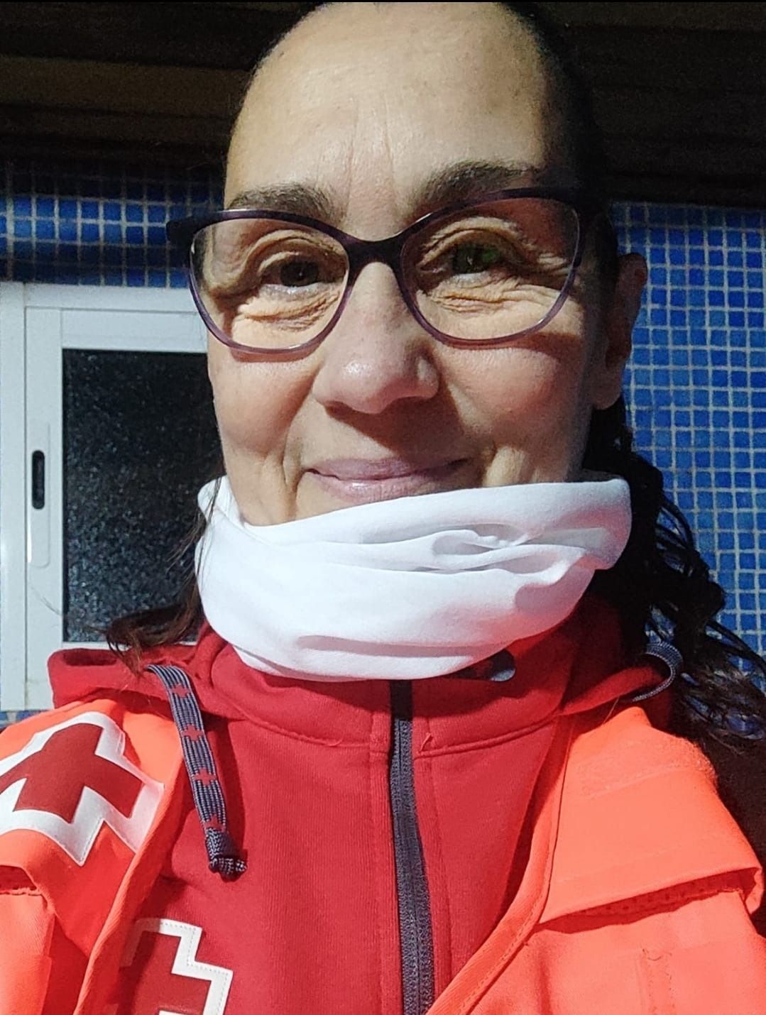 Una mujer que lleva gafas y una chaqueta roja lleva una bufanda blanca alrededor del cuello.