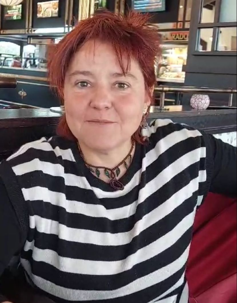 Una mujer pelirroja lleva una camisa a rayas blancas y negras.