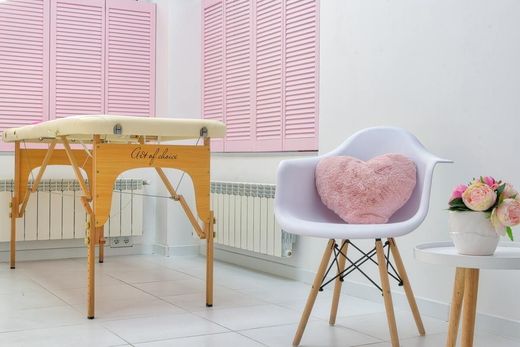 Una silla con una almohada en forma de corazón encima está en una habitación con una mesa de masajes.