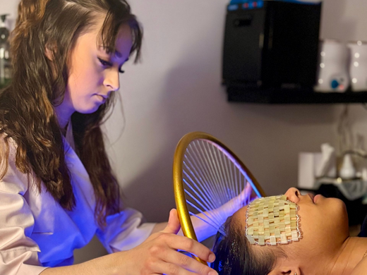 Une esthéticienne professionnelle utilise un anneau de luminothérapie bleue au-dessus d'une cliente.