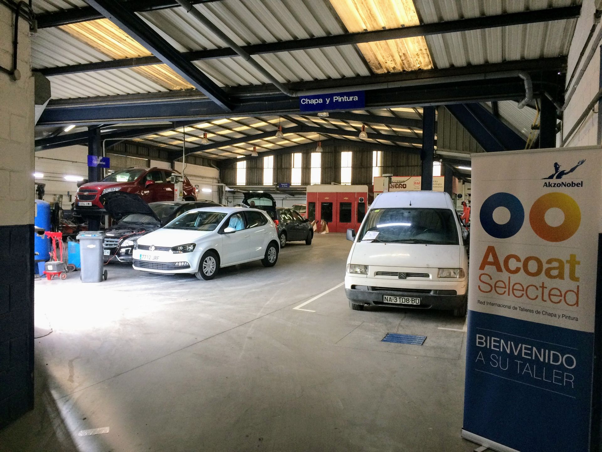 Un coche azul en un garaje con varios elevadores de vehículos y herramientas.