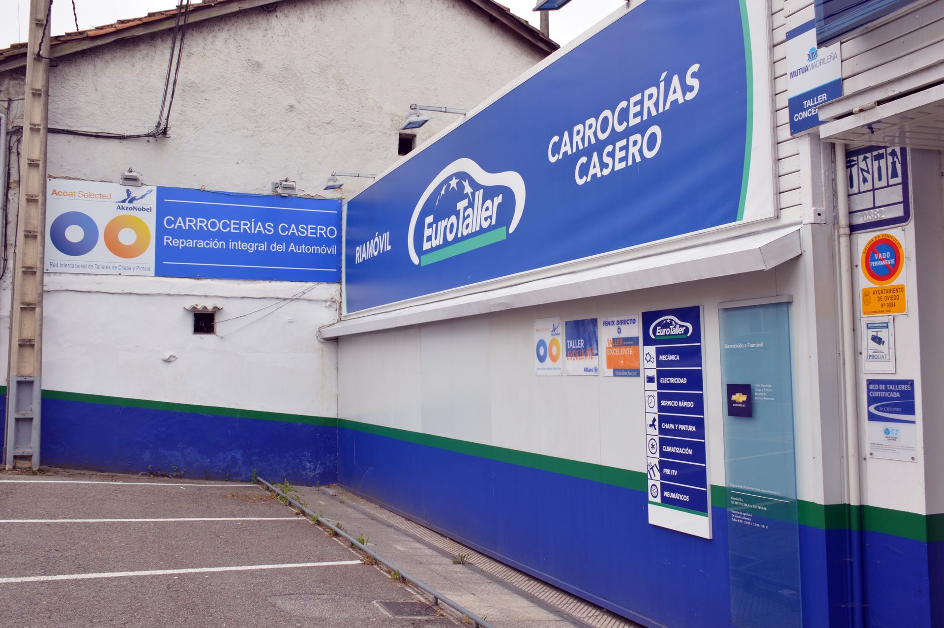 Bahía de lavado de vehículos con puerta azul y un coche plateado estacionado en el interior.