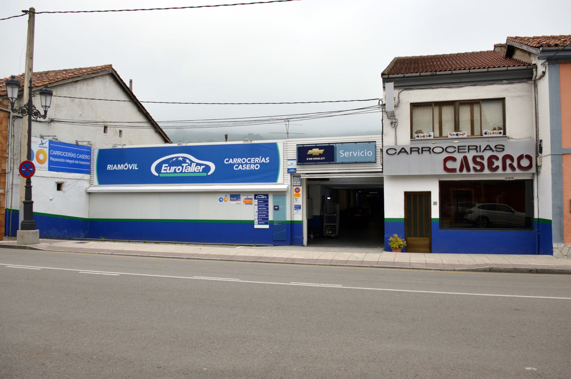 Dos cabinas de pintura de automóviles en un gran entorno industrial: una roja y otra blanca/de vidrio.