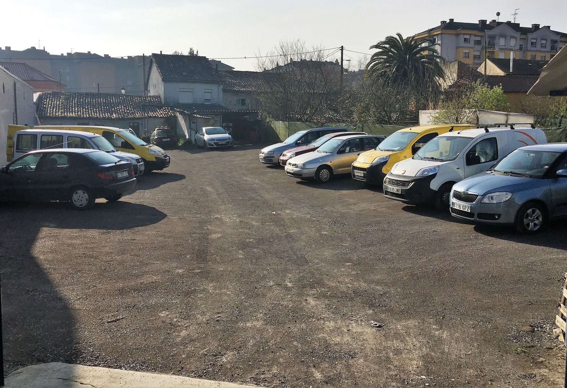 Auto en taller con daños en la parte frontal, al lado de un auto negro y un camión.