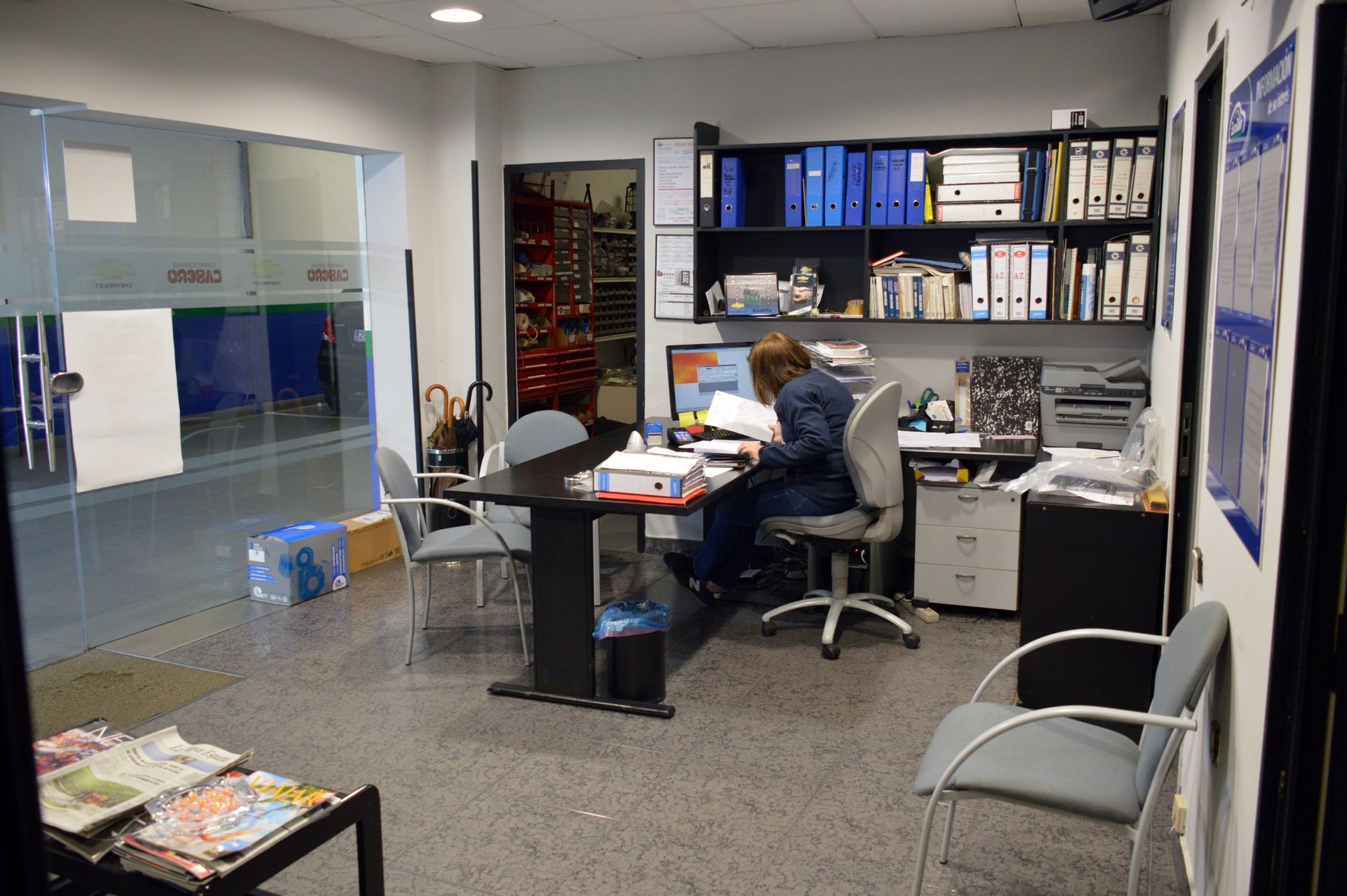 Sala de espera con cafetera, dispensador de agua, sillas y puerta abierta.