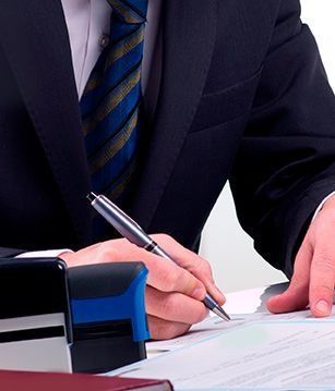 Un hombre con traje y corbata está escribiendo en un trozo de papel con un bolígrafo.