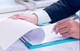 Una persona está escribiendo en un portapapeles con un bolígrafo.