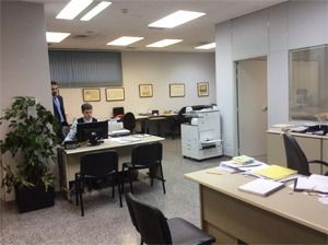 Un grupo de personas están sentadas en escritorios en una oficina.