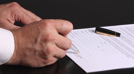 Una persona está firmando un documento con un bolígrafo.